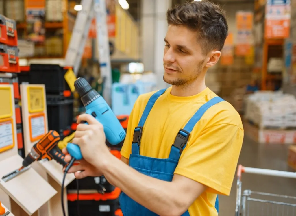 A man holding drill in a hardware store