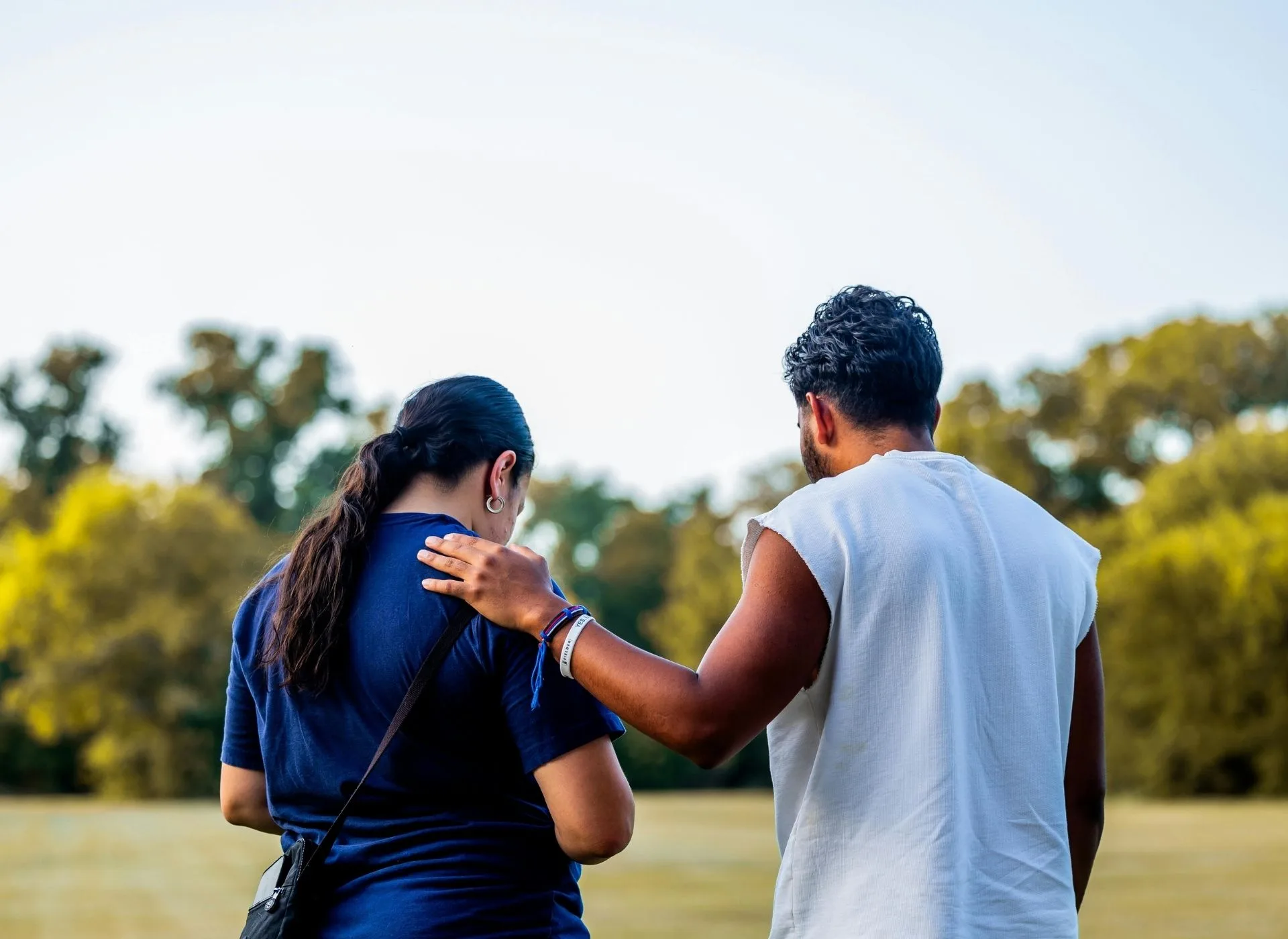 A man and lady stood outside with a hand on her shoulder 
